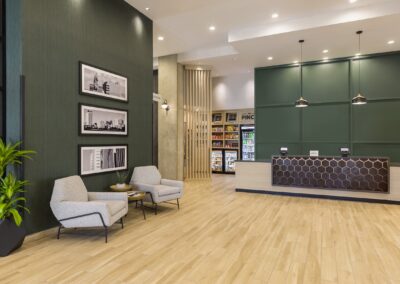 Hotel lobby with dark green walls and blonde wood floors and desk